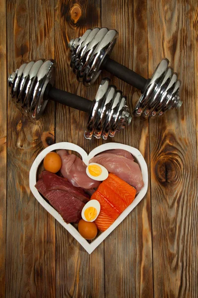 Proteinler ve halter. Balık, peynir, yumurta, et, tavuk kalp ahşap arka plan üzerinde — Stok fotoğraf
