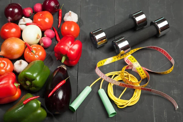 Sport e dieta. Uno stile di vita sano. Verdure, manubri. Peperoni, pomodori, aglio, ravanello di cipolla su fondo nero — Foto Stock