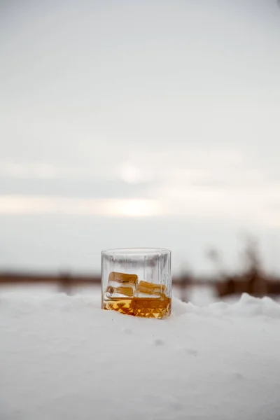 Szklankę whisky z lodem w śniegu na tło zima. — Zdjęcie stockowe