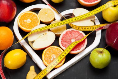 Diyet, meyve ve santimetre siyah bir zemin üzerine