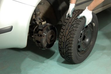 Tekerlek değiştiren bir atölyede araba tamircisi.