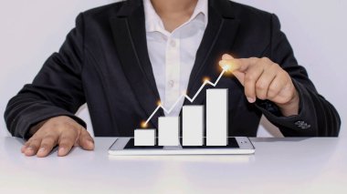 İşadamları, şirketin gelecekteki büyüme planları da dahil olmak üzere tabletteki grafiğe işaret ediyorlar. İş geliştirme fikirleri başarı ve mali büyümeyi artırıyor..