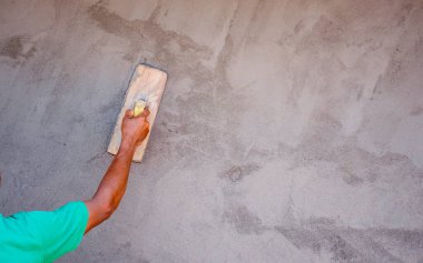 Ev inşaatı, çalışma fikirleri ve konut inşaatı için duvarları alçılamak için alçı kürek kullanan işçilerin yakın çekimleri.