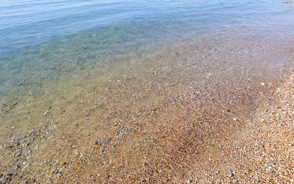 Schöner Hintergrund des blauen ruhigen Meeres mit kleinen Fischen, Sand und — Stockfoto