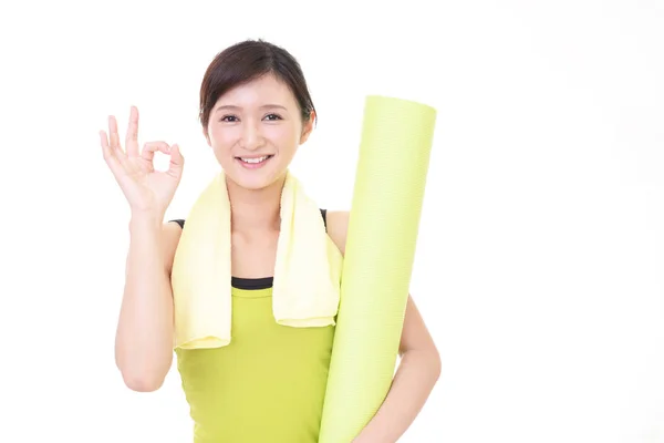 Женщина с ковриком для йоги в спортзале — стоковое фото
