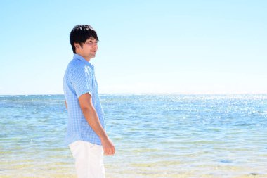 Sahilde gülümseyen Asyalı adam