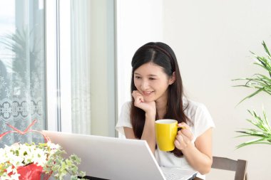 Gülümseyen kadın dizüstü bilgisayar kullanıyor.