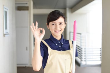 Bir süpürge ile Asya ev kadını gülümseyen