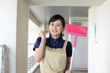 Bir süpürge ile Asya ev kadını gülümseyen