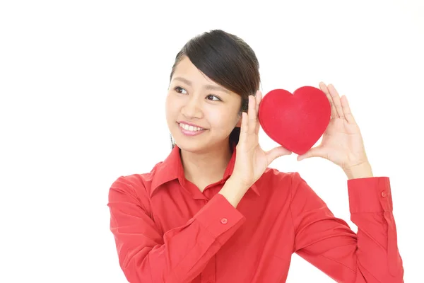 Mulher sorridente com um coração vermelho — Fotografia de Stock