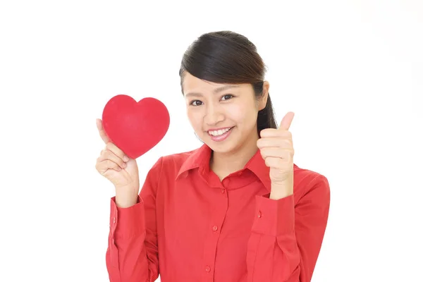 Mulher sorridente com um coração vermelho — Fotografia de Stock