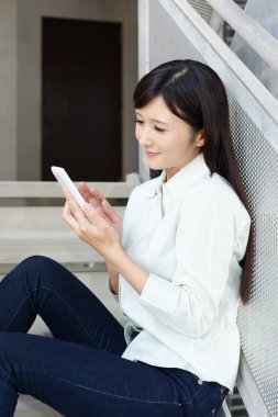 Bir akıllı telefon kullanan gülümseyen kadın