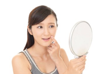 Asyalı kadın aynada yüzüne bakıyor.