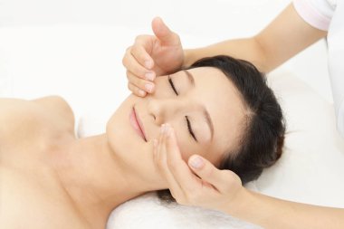 güzel bir genç kadın kapalı gözlerle yüz masajı bir spa salonda alma 