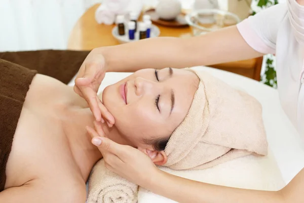 Güzel genç bayan yüz masajı yaptırıyor.