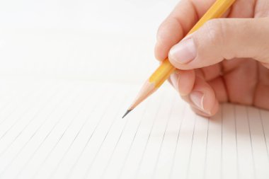 Not defterine kalem yazan bir kadın el.