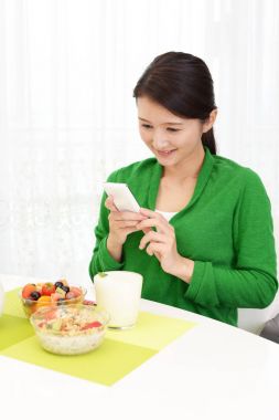 Mutlu genç kadın kahvaltı yapıyor.