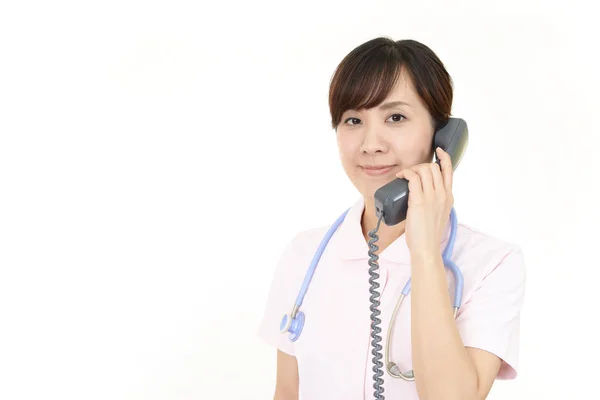 Smiling female nurse with a phone