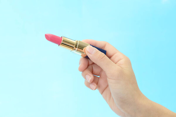 Женщина держит помаду.
