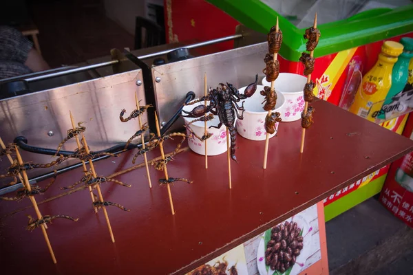 ZHUJIAJIAO, CHINA - AUGUST 30, 2016: Scorpions insects and bugs on spits are offered to shopping tourists as food by a vendor in the market street stall in Zhujiajiao, China, on August 30, 2016 — Stock Photo, Image