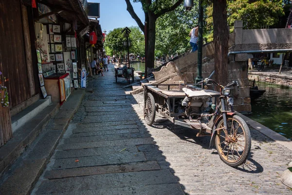 Zhujiajiao, Kína - augusztus 30, 2016: Rozsdás háromkerekű áruszállítás elektromos kerékpár parkoló csatorna töltésén ősi víz város Zhujiajiao, Kínában, a 2016. augusztus 30.. — Stock Fotó