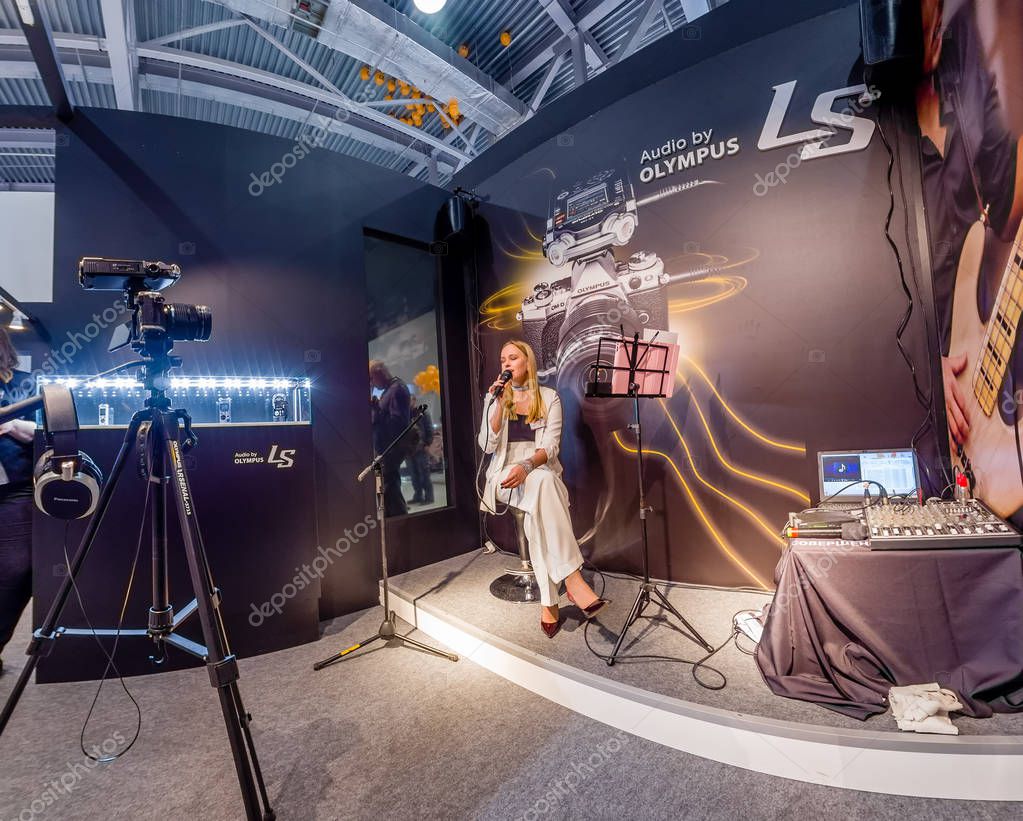 MOSCOW, RUSSIA - APRIL 21, 2017: Unidentified singer demonstrates LS-100 stereo audio recorder at Art Space booth of Olympus company at PhotoForum 2017 trade show in Moscow, Russia on April 21, 2017