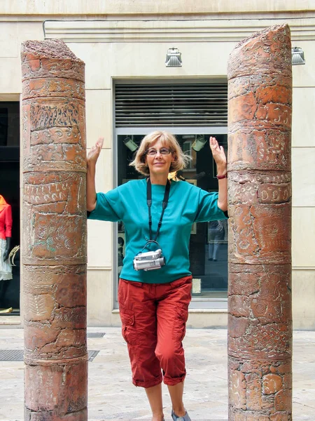 Bella donna turista felice matura con vecchia videocamera sul collo che viaggia a Palma di Maiorca rimane tra due colonne antiche — Foto Stock
