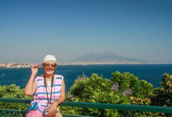 Felice donna turista matura che viaggia in Italia con una videocamera sul collo sulla baia di Napoli e sullo sfondo della montagna del Vesuvio — Foto Stock