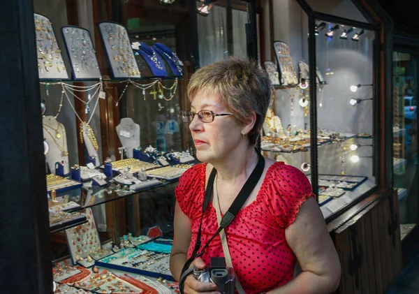 Donna turista matura che viaggia in Italia guarda la vetrina della gioielleria d'oro sul ponte Ponte Vecchio a Firenze — Foto Stock