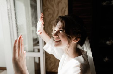 Genç ve güzel bir gelinin portresi. Düğün makyajı. Güzel kız damadı beklerken dairelerde düğün töreni için giyinir ve toplanır. Gelinin sabahı