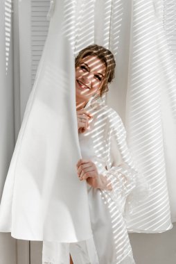 Balkonda genç ve güzel bir gelinin portresi. Güzel kız damadı beklerken dairelerde düğün töreni için giyinir ve toplanır. Gelin elbisesine bakıyor. Gelinin sabahı