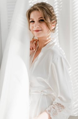 Balkonda genç ve güzel bir gelinin portresi. Güzel kız damadı beklerken dairelerde düğün töreni için giyinir ve toplanır. Gelin elbisesine bakıyor. Gelinin sabahı