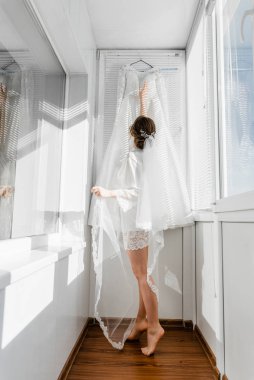 Balkonda genç ve güzel bir gelinin portresi. Güzel kız damadı beklerken dairelerde düğün töreni için giyinir ve toplanır. Gelin elbisesine bakıyor. Gelinin sabahı