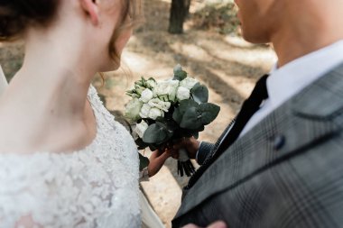 Çekici bir çift düğünlerini ormanda kutluyor. Gelin ve damadın birlikte el ele tutuşup birbirlerine baktıkları portresi.