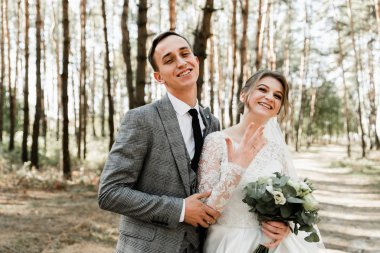 Çekici bir çift düğünlerini ormanda kutluyor. Gelin ve damadın bir arada el ele tutuşup birbirlerine baktıkları portresi. Evlilik yüzüğü.