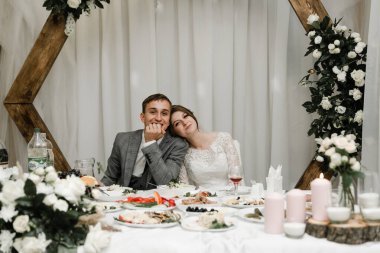 Düğünlerini restoranda kutlayan çekici bir çift. Gelin ve damadın el ele tutuşup birbirlerine baktıkları portre.