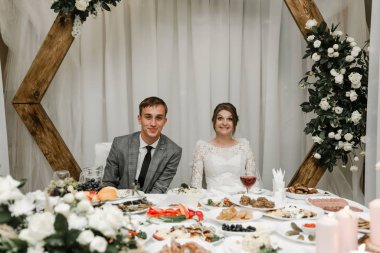 Düğünlerini restoranda kutlayan çekici bir çift. Gelin ve damadın el ele tutuşup birbirlerine baktıkları portre.