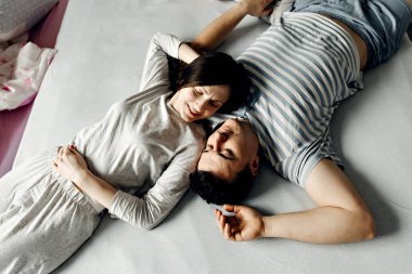 Yatakta birbirini seven bir çift, mutlu genç bir aile sabah yatakta erken uyanır, uyanan bir çiftin üst görüntüsü, karı koca gülümsüyor ve şefkatle sarılıyorlar, yataktaki çifti dikizliyorlar.