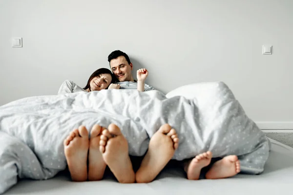 portrait of a young family in bed,happy father and mother lie with their daughter in bed in the early morning,young family hugs tightly,positive morning in a happy family