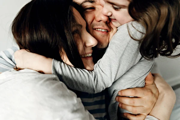 İnsanlar, aile ve sabah konsepti. Ailesi evde yastık kavgası yapan mutlu çocuk. Yatakta yastık kavgası yapan aile. Ebeveynler boş zamanlarını kızlarıyla geçirirler..