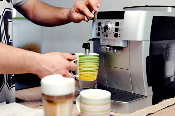home coffee machine pours a mug of coffee,man\'s hand presses the start button of the coffee machine,hot coffee is poured into a glass,coffee at home