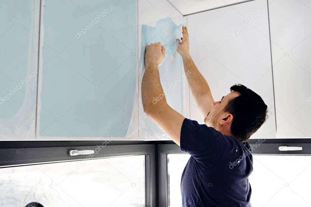 removal of a protective film,protective film,man removes kitchen protective film,new white kitchen sealed in protective film,hands of man removing protective glass