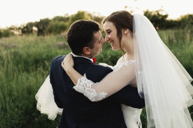 Mutlu damat yaz parkında gelin yetiştiriyor. Adam kadını kollarına alıp kucakladı. Parkta yeni evli bir çift. Yeni evlendim. Parkta yürü ve sarıl. Yeni evliler eğleniyor. Kırsal düğün