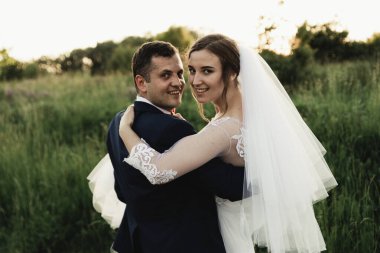 Mutlu damat yaz parkında gelin yetiştiriyor. Adam kadını kollarına alıp kucakladı. Parkta yeni evli bir çift. Yeni evlendim. Parkta yürü ve sarıl. Yeni evliler eğleniyor. Kırsal düğün