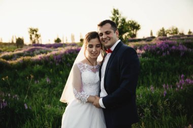 Gelin ve damat gün batımında kucaklaşıyor. Mutlu gelin ve damat gülümsüyor. Düğünden sonra mutlu gelin ve damat. Düğün günü.