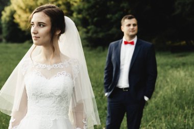 Gelin ve damat gün batımında kucaklaşıyor. Mutlu gelin ve damat gülümsüyor. Düğün gününden sonra mutlu gelin ve damat. Çiçekli bir tarlada güzel bir çift, ormanda genç bir çift, doğada gelin ve damat.