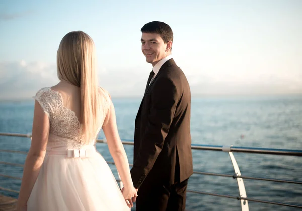 portrait of the bride and groom,newlyweds on the background of the sea,happy wedding couple on sea beach,newlyweds are hugging on the wedding day after the ceremony,wedding dresses on the bride and groom,wedding day