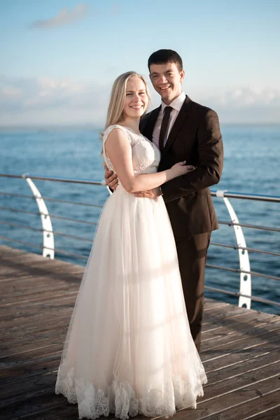 portrait of the bride and groom,newlyweds on the background of the sea,happy wedding couple on sea beach,newlyweds are hugging on the wedding day after the ceremony,wedding dresses on the bride and groom,wedding day