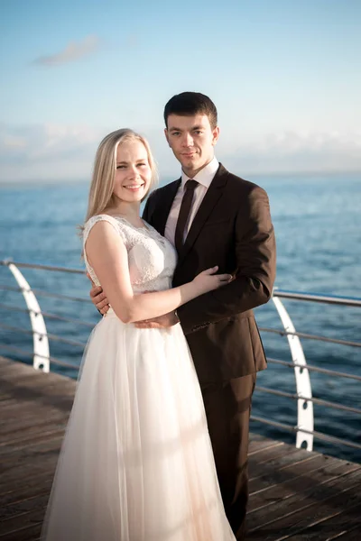 portrait of the bride and groom,newlyweds on the background of the sea,happy wedding couple on sea beach,newlyweds are hugging on the wedding day after the ceremony,wedding dresses on the bride and groom,wedding day