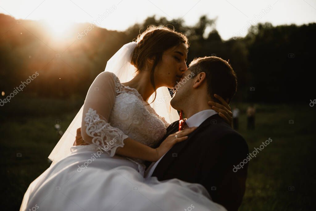 Happy bridegroom raises bride in summer park. man raised and hug woman to her arms. Newly wedded couple in the park. Just married. Walk in the park and hug. Newlyweds having fun. rustic wedding